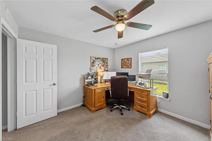 Office with ceiling fan and light carpet
