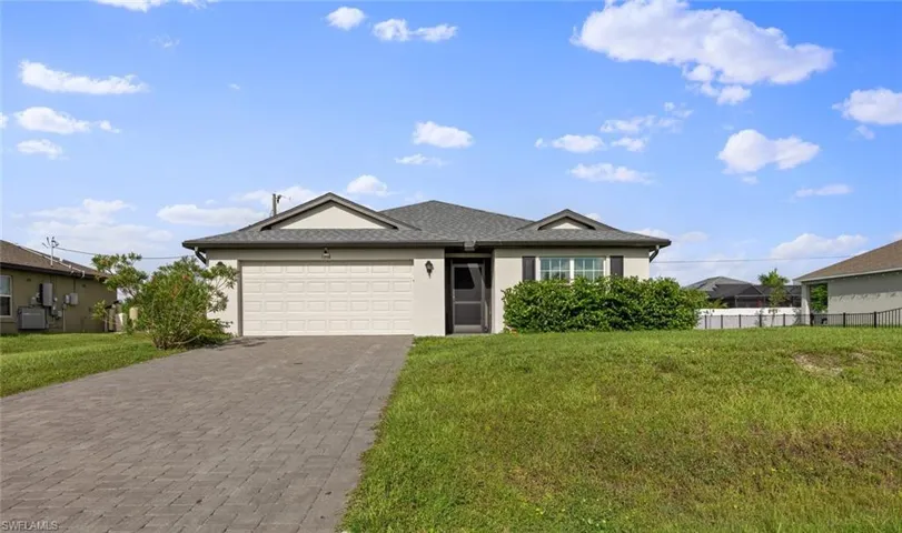 View of front of home with a front yard, cooling unit, and a garage