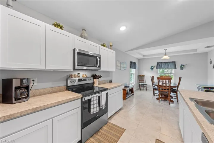 Kitchen featuring pendant lighting, white cabinetry, light tile patterned floors, stainless steel appliances, and sink
