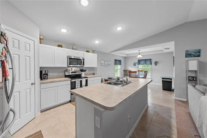 Kitchen with white cabinets, lofted ceiling, stainless steel appliances, and sink