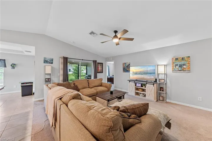 Living room featuring lofted ceiling, ceiling fan, and light tile patterned floors