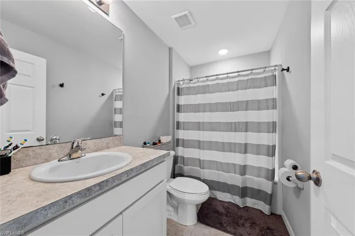 Bathroom featuring tile patterned flooring, walk in shower, toilet, and vanity