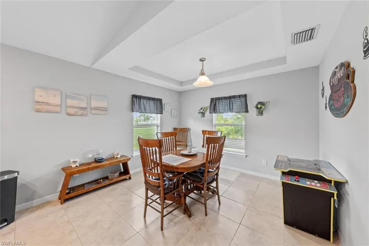 Dining area featuring light tile patterned floors and a raised ceiling