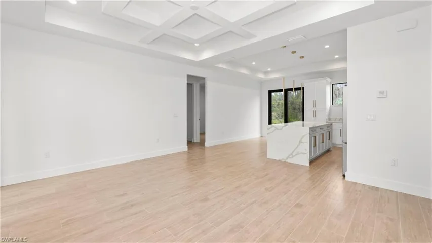 Unfurnished room with coffered ceiling, recessed lighting, light wood-style flooring, a raised ceiling, and beam ceiling