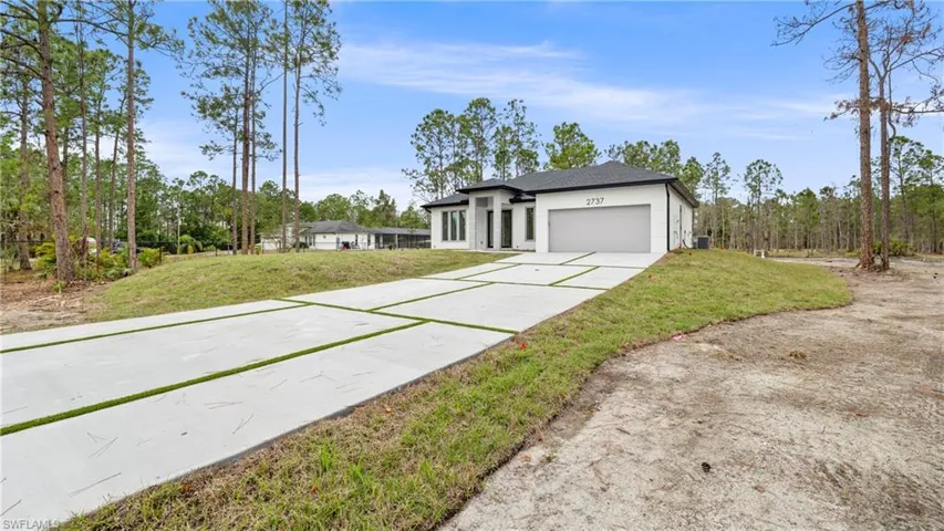 View of front of house with a front yard, driveway, an attached garage, and stucco siding