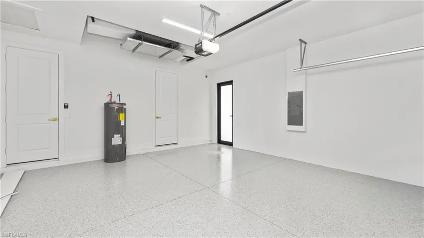 Garage with water heater, electric panel, and a garage door opener