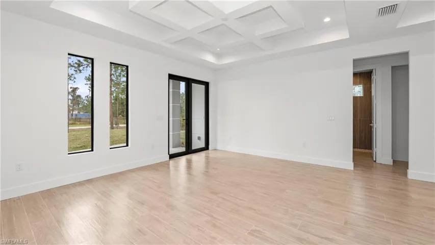 Spare room with coffered ceiling, light wood finished floors, beamed ceiling, and recessed lighting