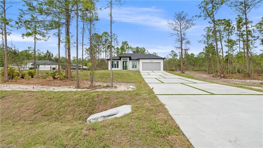 View of front of house featuring a front lawn, concrete driveway, and an attached garage