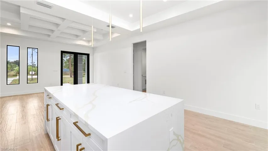 Kitchen featuring coffered ceiling, light wood-style floors, a skylight, white cabinets, and recessed lighting
