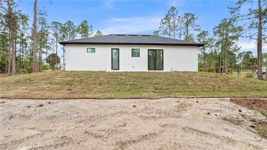 Back of property with a lawn and stucco siding