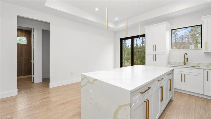 Kitchen featuring light wood-style flooring, light stone countertops, white cabinets, and recessed lighting
