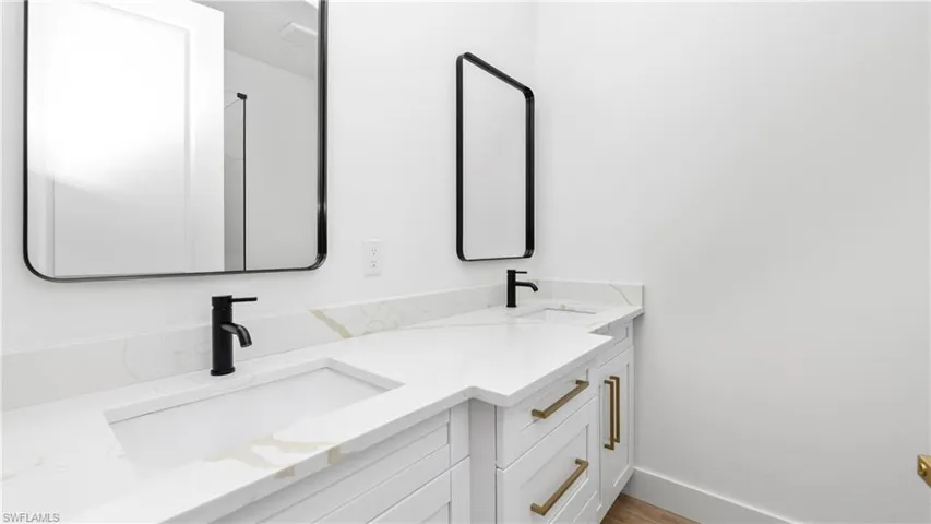 Full bath featuring double vanity and baseboards
