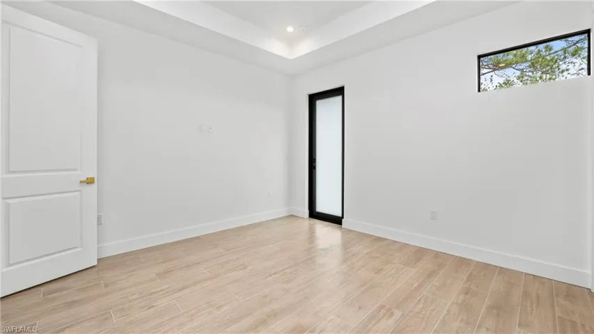 Empty room featuring light wood-style flooring, recessed lighting, and a tray ceiling