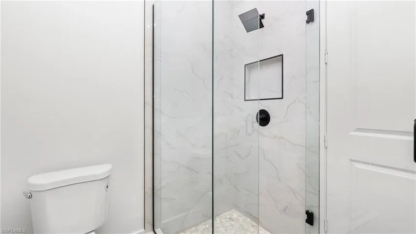 Bathroom with toilet and a marble finish shower