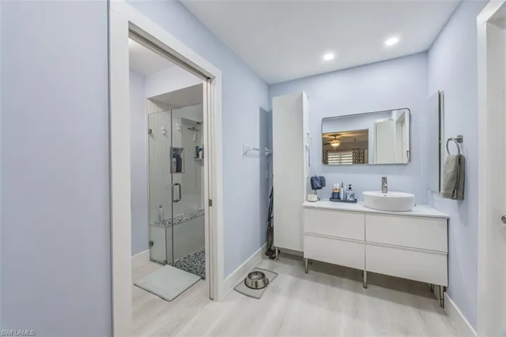 Bathroom with a shower stall, vanity, and light wood-style flooring