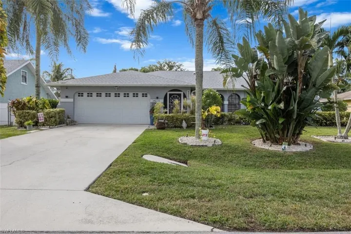 Ranch-style home featuring concrete driveway, a front yard, stucco siding, and a garage