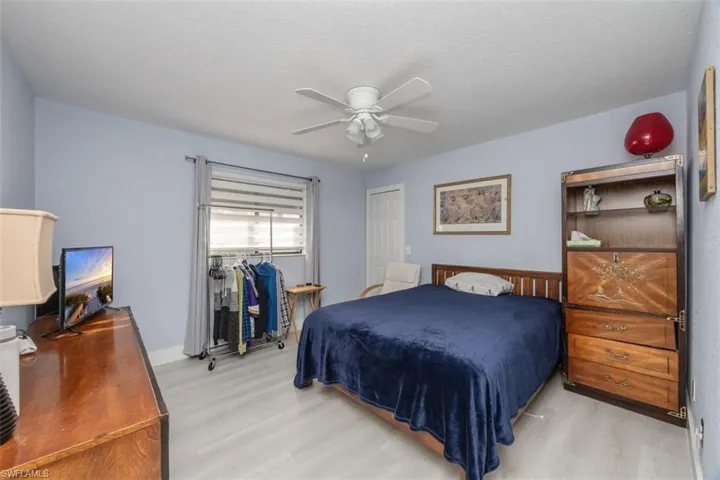 Bedroom with light wood-style floors, a ceiling fan, and a textured ceiling