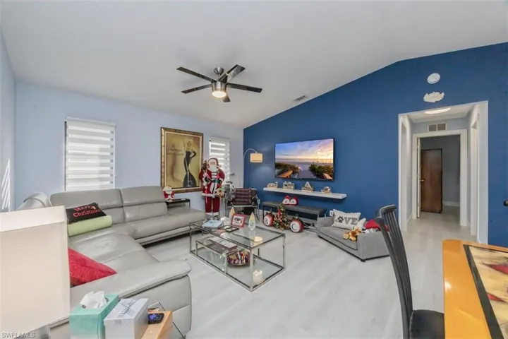 Living area featuring lofted ceiling, wood finished floors, and a ceiling fan