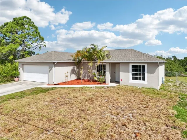 Ranch-style home featuring stucco siding, roof with shingles, driveway, a front lawn, and a garage