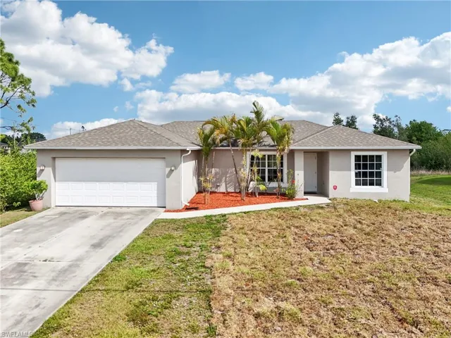 Ranch-style home with stucco siding, an attached garage, and a shingled roof
