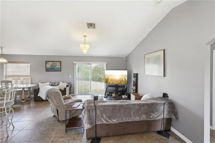 Living room featuring baseboards, lofted ceiling, and visible vents