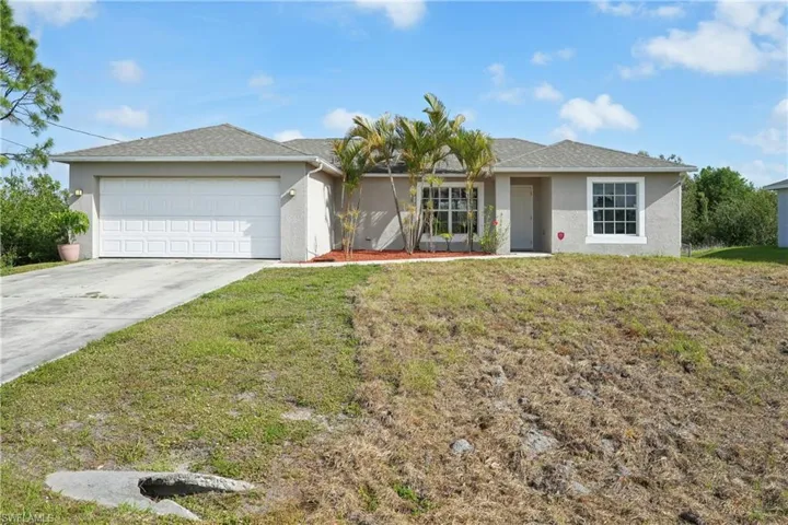 Ranch-style house featuring a garage, concrete driveway, stucco siding, and a front lawn