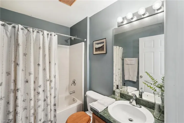 Bathroom featuring shower / tub combo with curtain, visible vents, toilet, and vanity