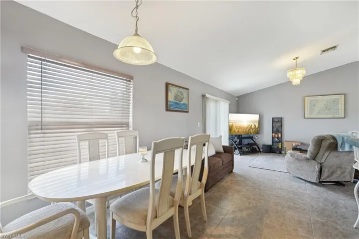 Tiled dining room with lofted ceiling and visible vents