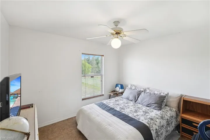 Bedroom with baseboards, tile patterned flooring, and a ceiling fan