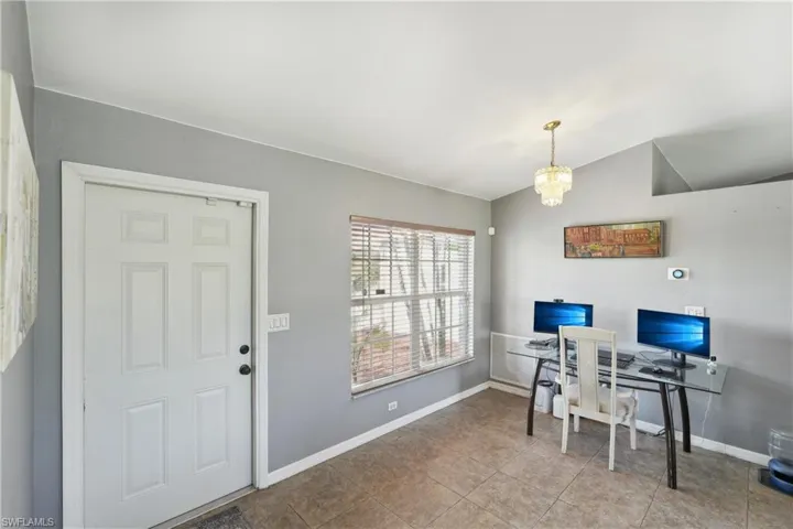 Tiled office space featuring a chandelier, baseboards, and vaulted ceiling