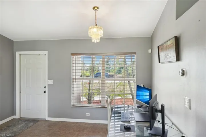 Tiled office with baseboards and a notable chandelier