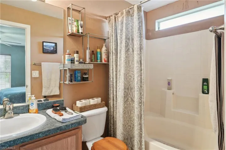 Bathroom featuring a ceiling fan, toilet, vanity, and shower / bath combo with shower curtain