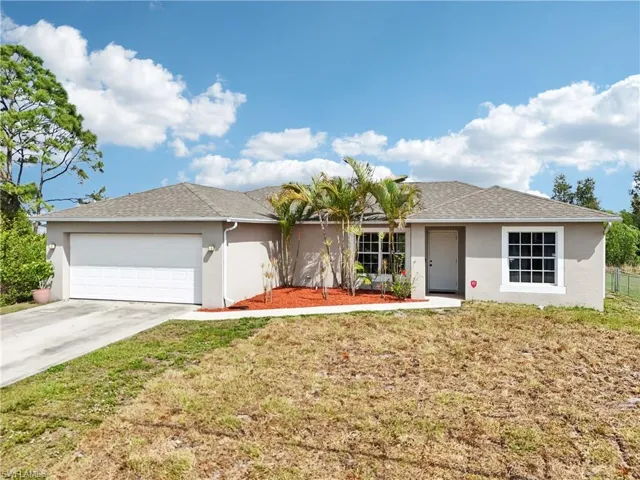 Ranch-style house featuring driveway, a garage, a front lawn, stucco siding, and a shingled roof