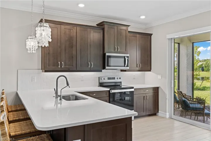 Kitchen with decorative backsplash, sink, dark brown cabinets, and stainless steel appliances