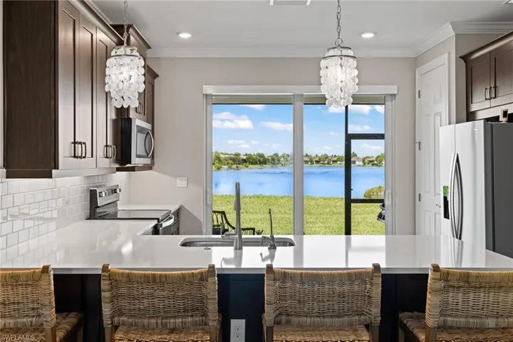 Kitchen featuring stainless steel appliances, an inviting chandelier, sink, decorative backsplash, and a water view