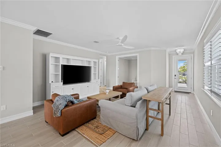 Living room with light hardwood / wood-style flooring, ceiling fan, and crown molding
