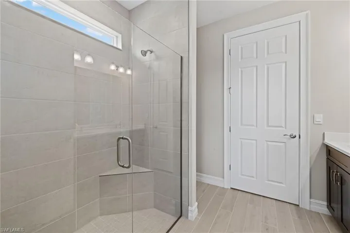 Bathroom with a shower with shower door, vanity, and hardwood / wood-style flooring