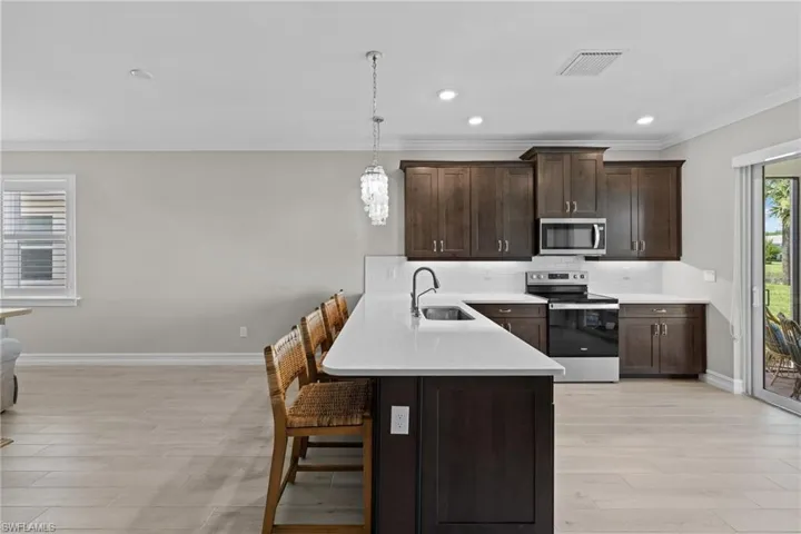Kitchen with a kitchen bar, stainless steel appliances, sink, kitchen peninsula, and backsplash