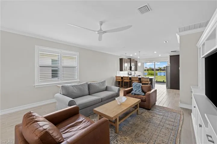 Living room with ceiling fan, crown molding, and light hardwood / wood-style flooring