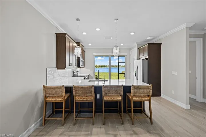 Kitchen featuring stainless steel appliances, a water view, light wood-type flooring, kitchen peninsula, and backsplash