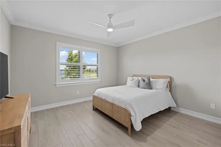 Bedroom featuring crown molding, light wood-type flooring, and ceiling fan