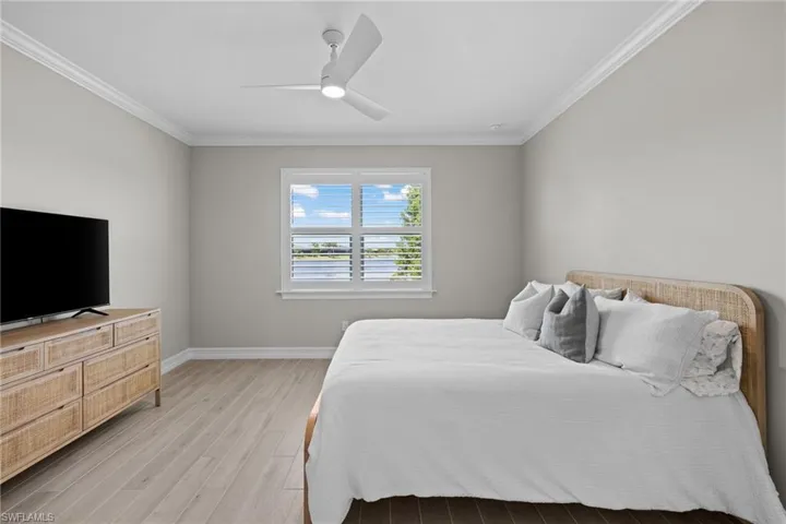 Bedroom with light hardwood / wood-style flooring, ornamental molding, and ceiling fan