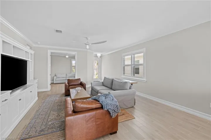 Living room with ornamental molding, light wood-type flooring, and ceiling fan
