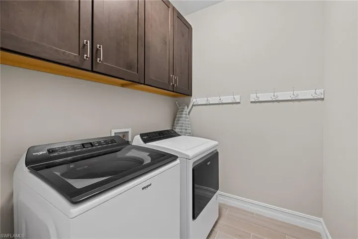 Laundry room featuring washing machine and clothes dryer, light hardwood / wood-style flooring, and cabinets