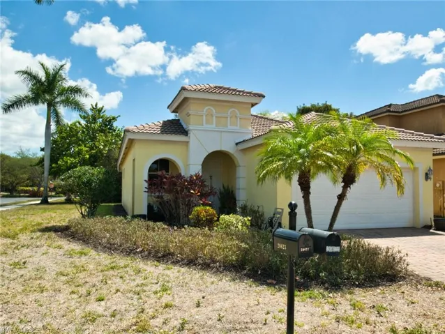 View of front of property featuring a garage, driveway, a tile roof, and stucco siding