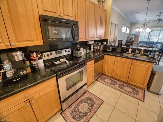 Kitchen with stainless steel appliances, dark stone countertops, a peninsula, open floor plan, and ornamental molding
