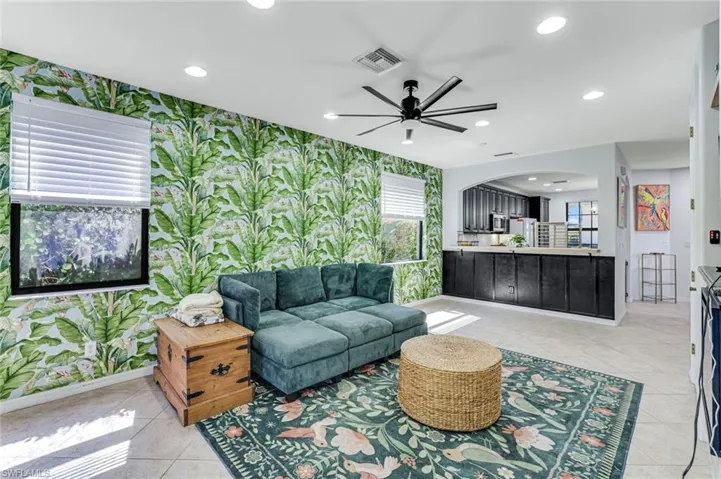 Living area with recessed lighting, ceiling fan, arched walkways, and wallpapered walls
