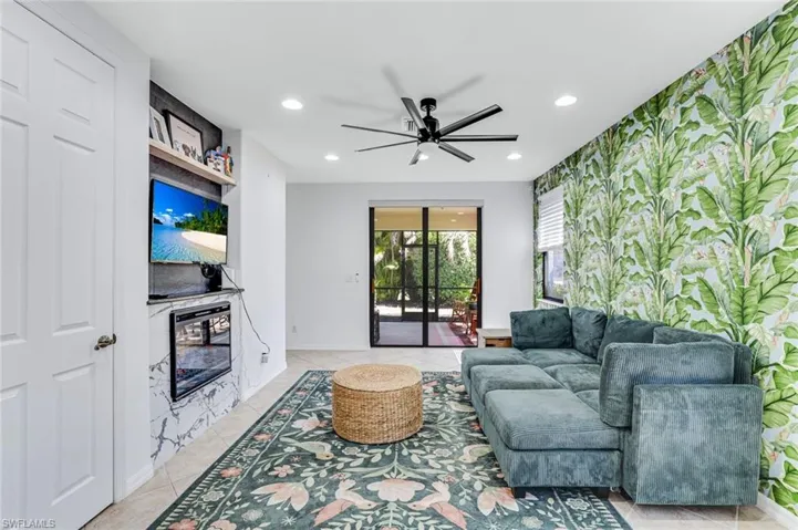 Living room featuring a ceiling fan, recessed lighting, wallpapered walls, light tile patterned floors, and an accent wall