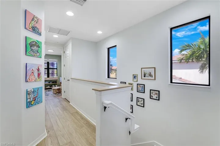 Hallway featuring an upstairs landing, light wood finished floors, and recessed lighting