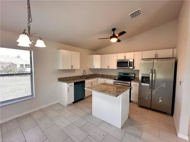 Kitchen featuring stainless steel appliances, dark stone countertops, white cabinets, ceiling fan, and lofted ceiling